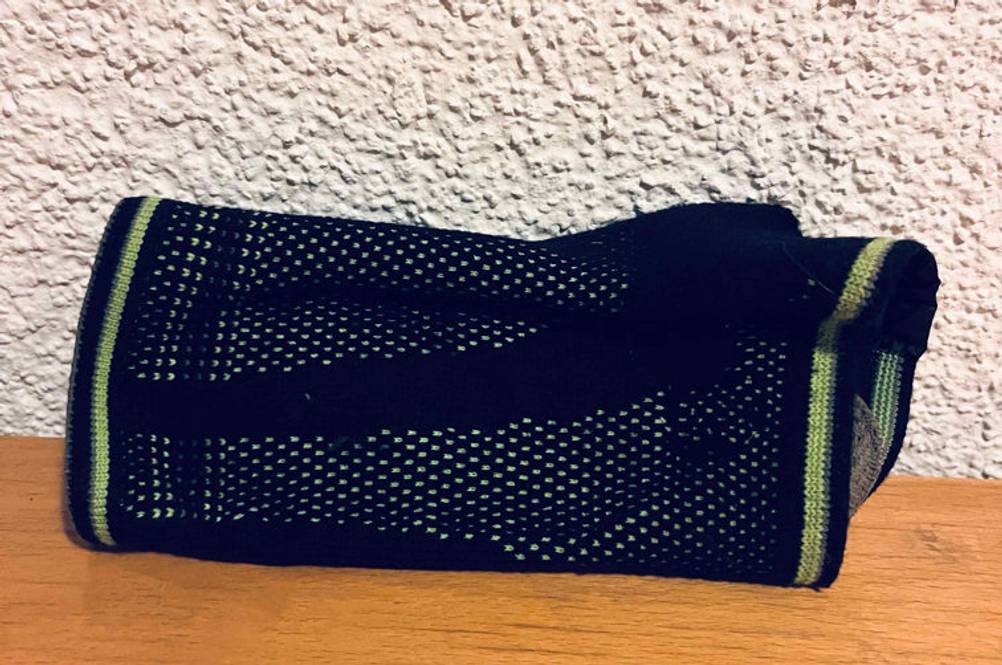 Schwarze, gewebte, getestete Inliner-Protektoren liegen auf einer Holzoberfläche vor weißer Wand.