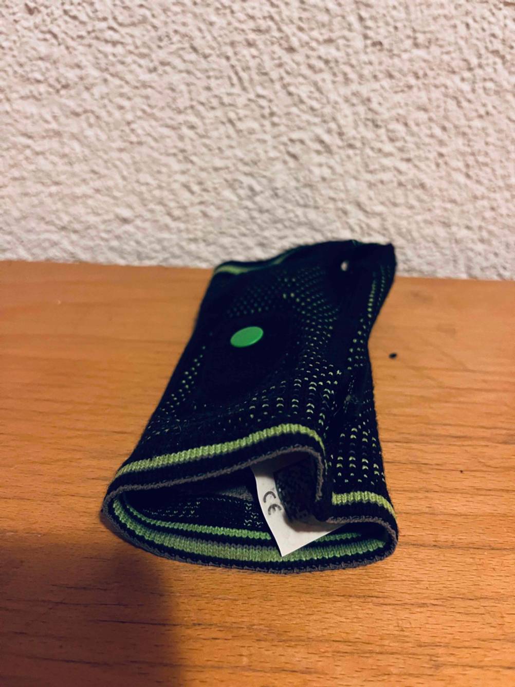 Nahaufnahme eines CE-Etiketts von einem schwarz-grünen Inliner-Protektor im Test, der auf einer Holzfläche liegt.