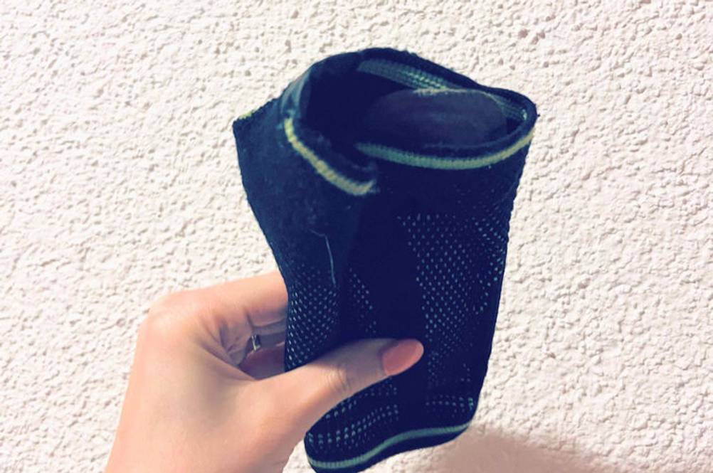 Inliner-Protektoren im Test: Hand hält ein Protektoren-Modell im Netzstrumpfdesign vor einer weißen Wand.