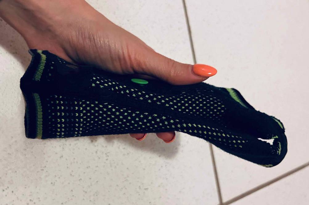 Inliner-Protektoren-Test: Hand hält ein Netzstrumpf-Modell vor weißem Fliesenboden.