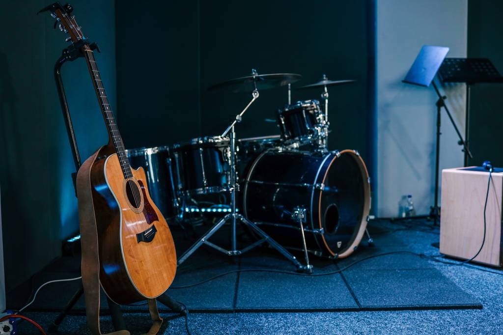 Eine Gitarre und ein Schlagzeug stehen in einem Proberaum.