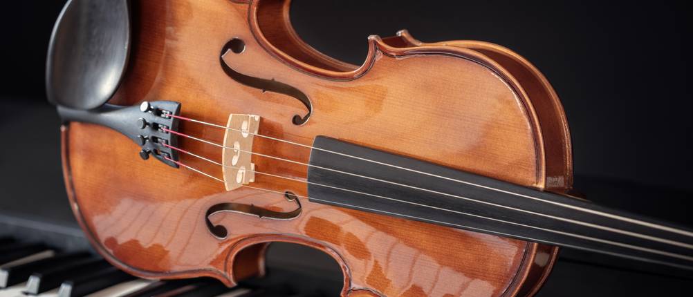 Eine Violine liegt auf den Tasten eines Klaviers.
