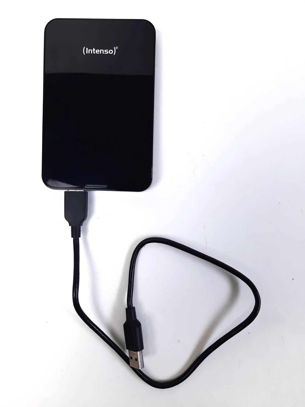 Festplatte getestet: Eine Intenso-Festplatte von oben mit angeschlossenem Datenkabel auf einer weißen Fläche.