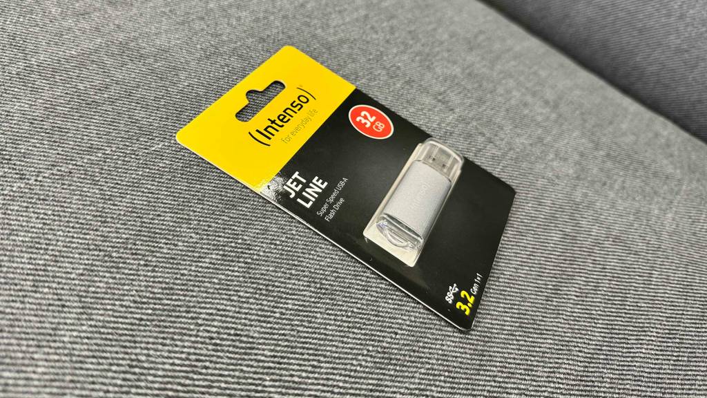 USB-3.2-Sticks im Test: ein Modell der Marke Intenso liegt verpackt auf einem grauen Stoffbezug.