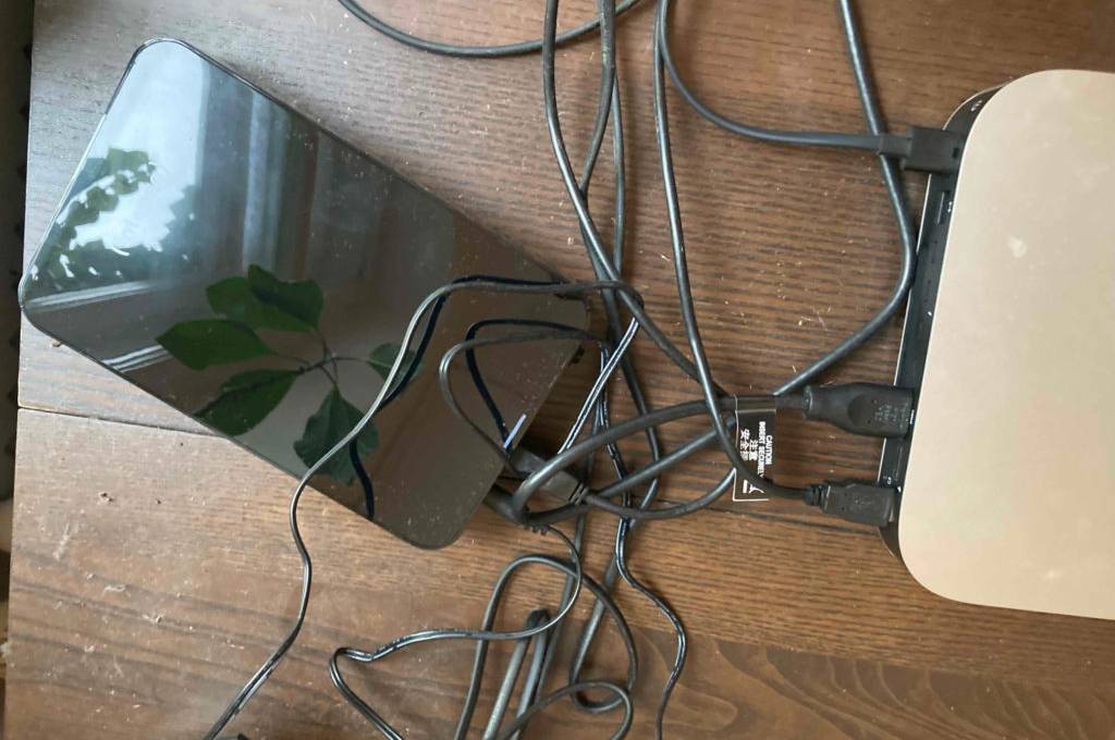 Externe, getestete 8-TB-Festplatte in Schwarz liegt auf einer Holzoberfläche und ist mit einem Computer verbunden.