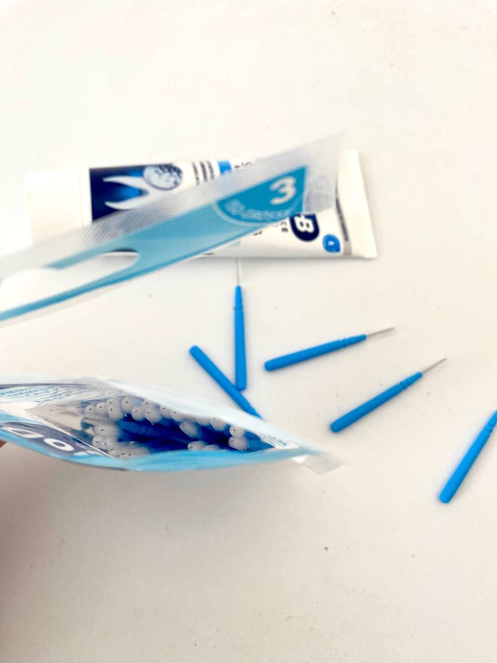 Interdentalbürsten getestet: Auf einer hellen Fläche steht eine aufgerissene Packunf und einige einzelne Interdentalbürsten liegen daneben.