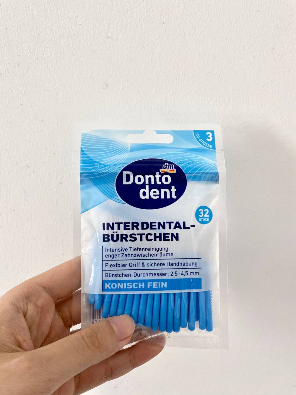 Eine Hand hält eine Packung mit getesteten Interdentalbürsten.