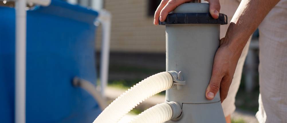 Intex-Filterpumpe-Test: Eine Filterpumpe wird neben einem Aufstellpool montiert.