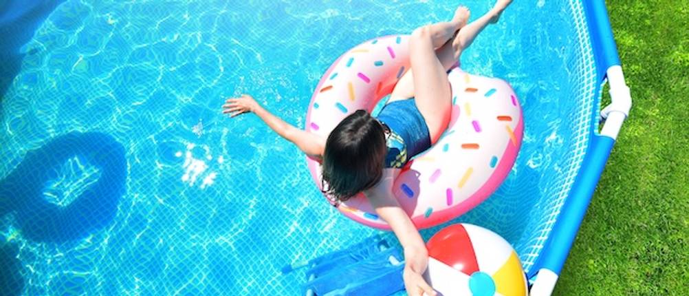 Intex-Pool getestet: Ansicht eines Mädchens von oben, das mit einem Schwimmreifen in einem Frame-Pool spielt.