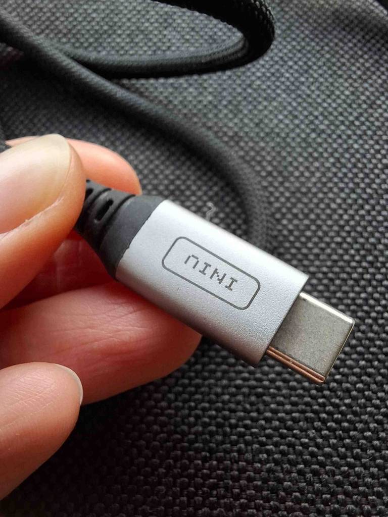 Eine Hand zeigt den silberfarbigen Stecker eines grauen USB-C-Schnellladekabels im Test. 