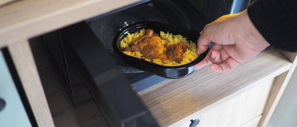 Inverter-Mikrowelle-Test: Ein Mann stellt ein Essen in eine Mikrowelle.