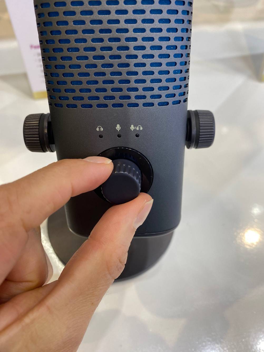 Im Test: Hand dreht am Einstellrad für Kopfhörer und Mikrofon eines USB Kondensatormikrofons.