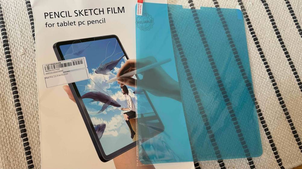 iPad-Pro-12.9-Panzerglas getestet: Das Glas liegt neben der Originalverpackung auf einem gestreiften Teppich.