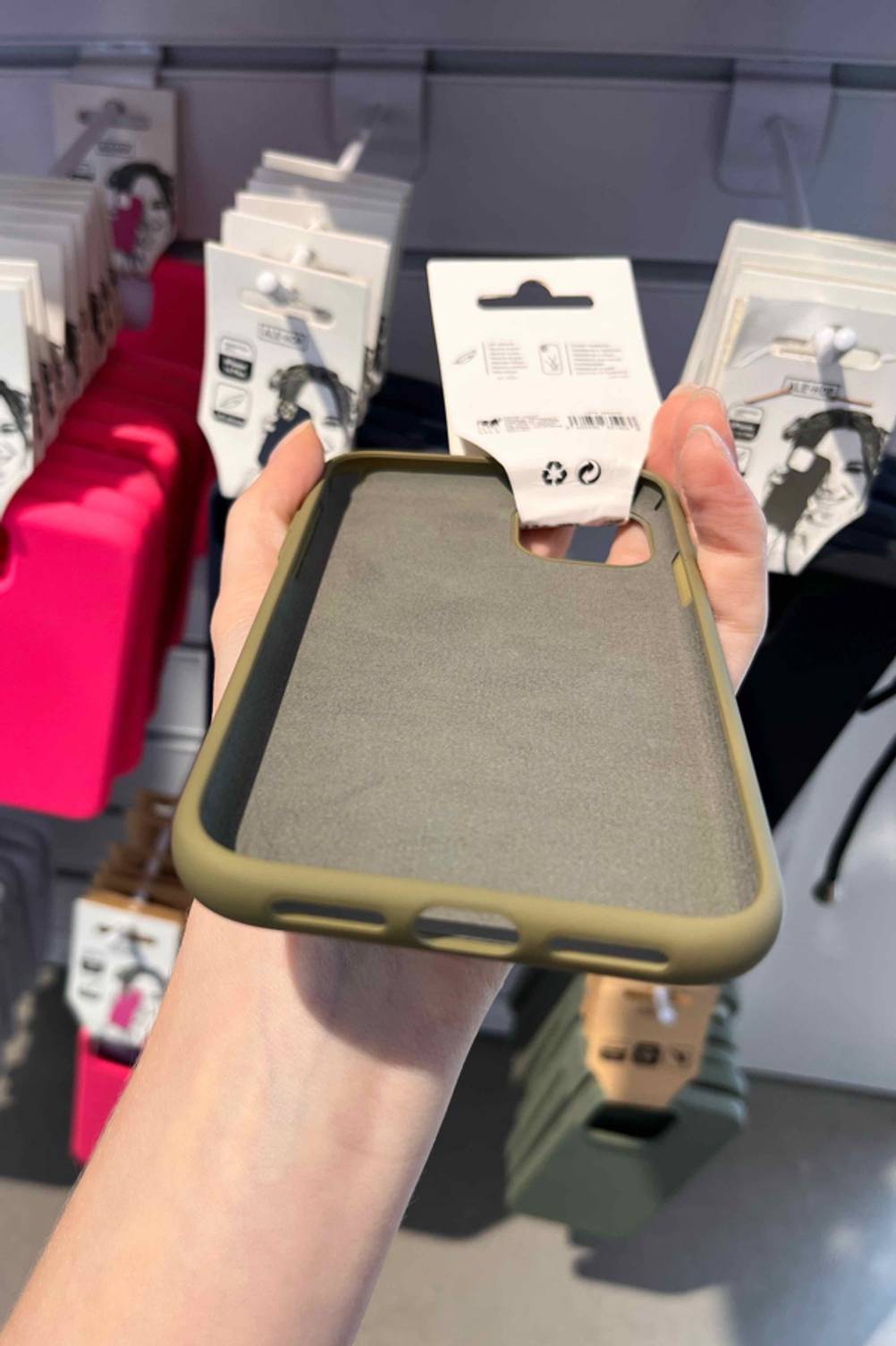 Nahaufnahme der Aussparungen am Ende einer getesteten iPhone 11 Pro Max Hülle von einer Hand vor ein Regal gehalten.