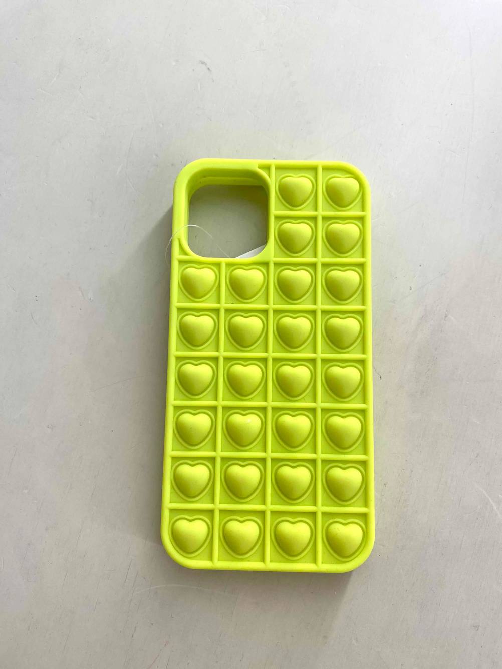 Eine gelbe iPhone-12-Hülle im Test von oben auf einer weißen Fläche.