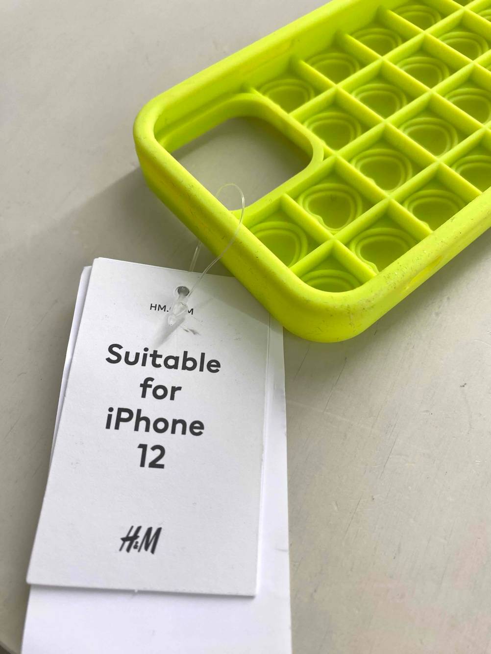 Auf dem Boden liegt eine getestete iPhone-12-Hülle mit Preisschild. 