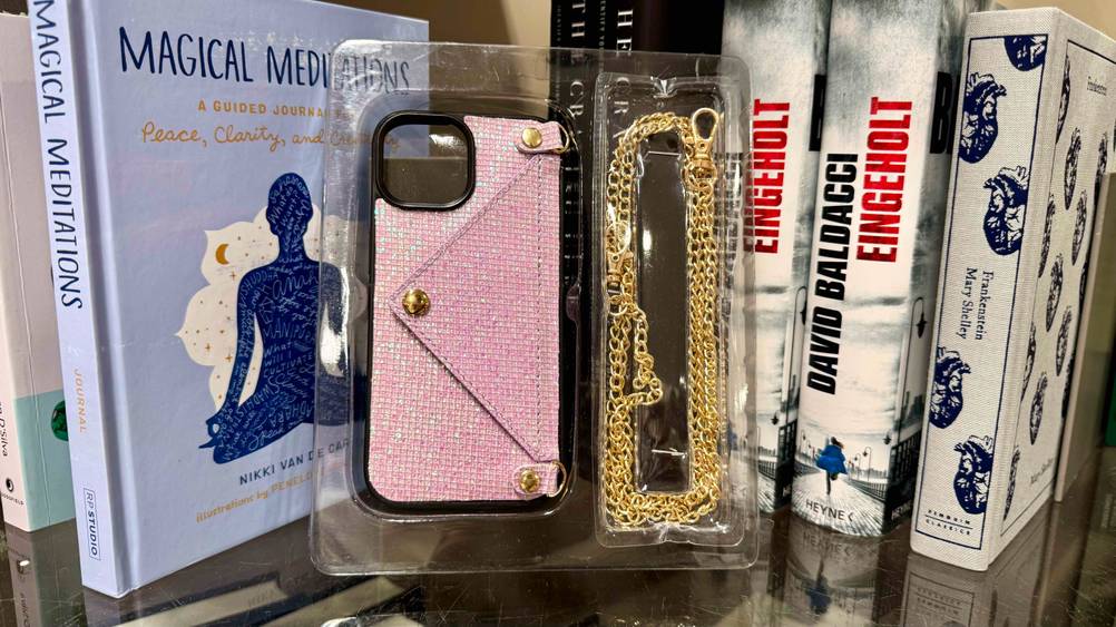 iPhone-14-Plus-Hülle im Test: Eine Packung mit Hülle und Kette vor Büchern.