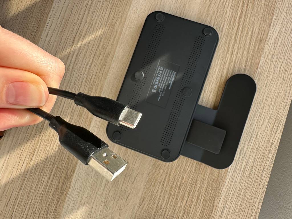 Getestet: Eine Hand hält ein Kabel vor die Rückseite einer iPhone-Ladestation.