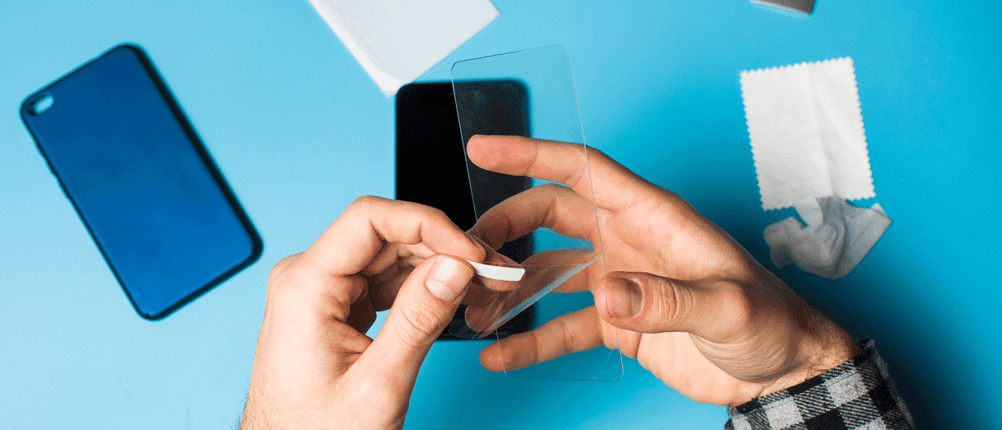 Mann klebt Handy-Schutzfolie auf
