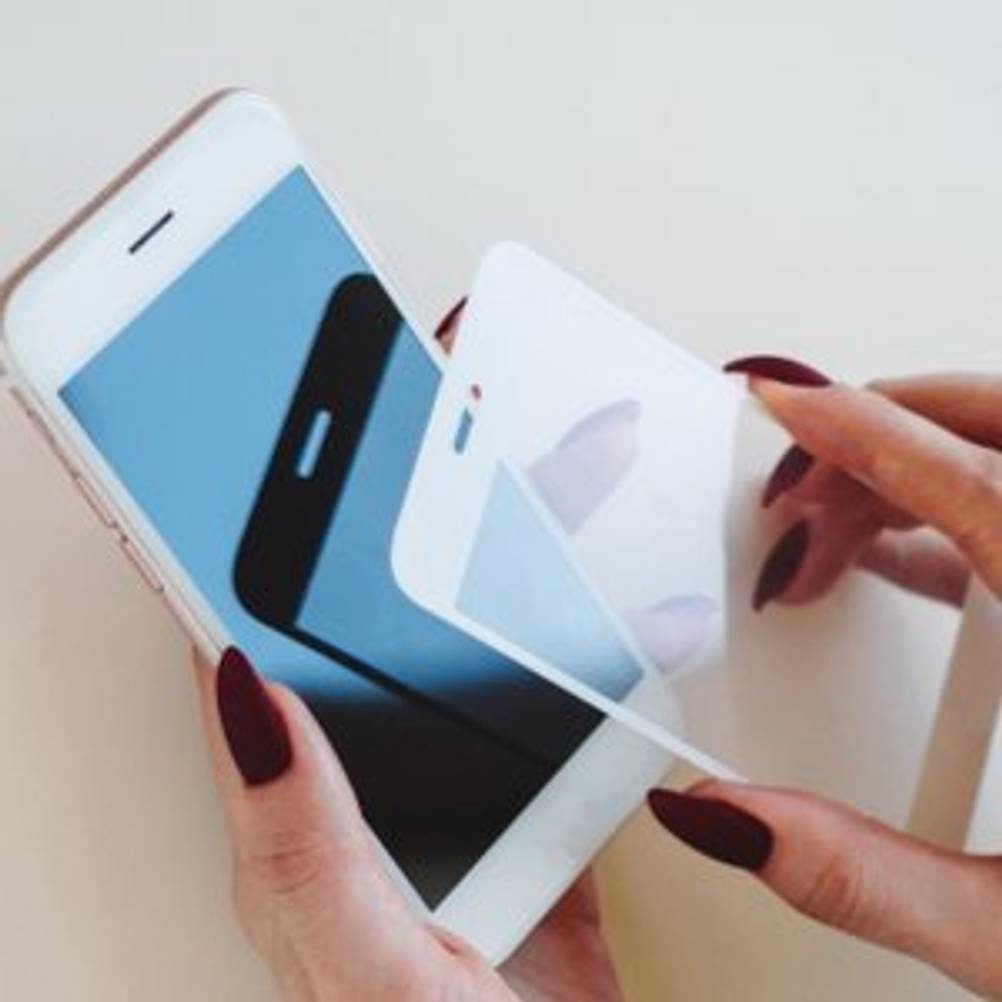 frau legt schutzfolie auf iphone
