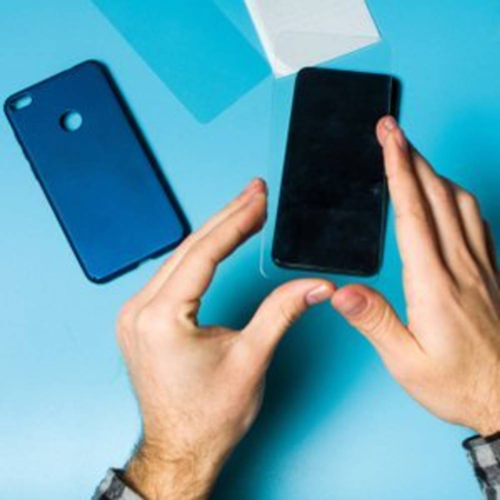 mann legt schutzfolie auf iphone