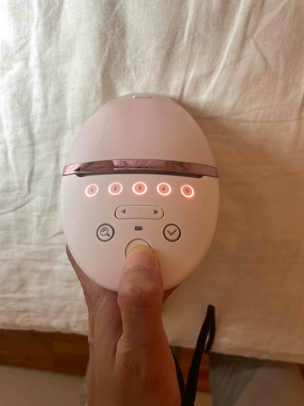 Nahaufnahme der Bedienelemente eines IPL-Gerätes im Test, ein Daumen drückt einen Knopf.