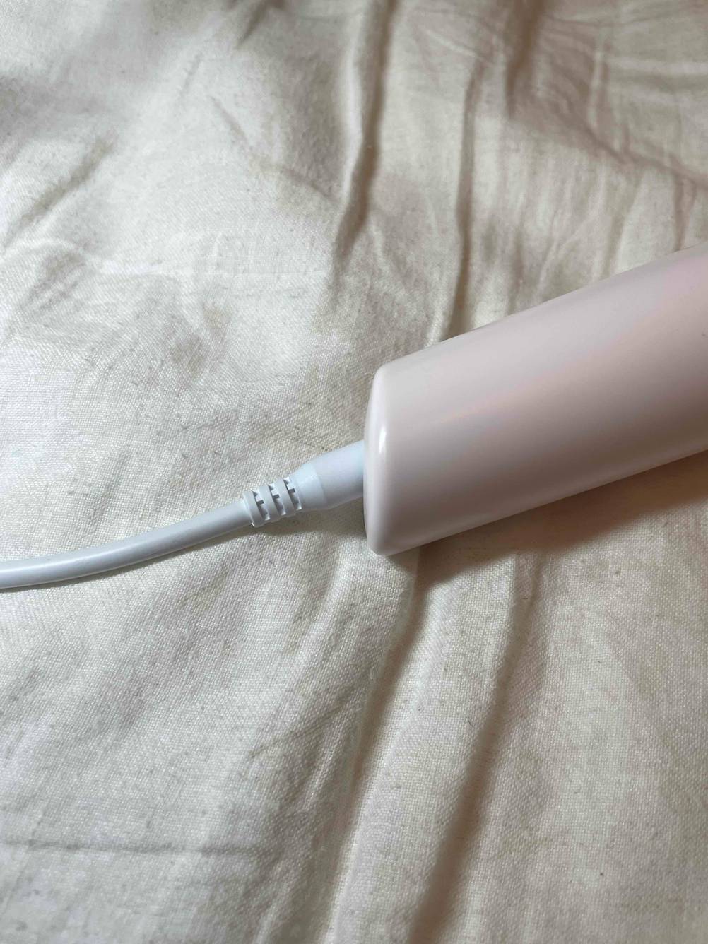 Nahaufnahme des Griffes mit Stromkabel eines getesteten IPL-Gerätes auf einer Stofffläche.