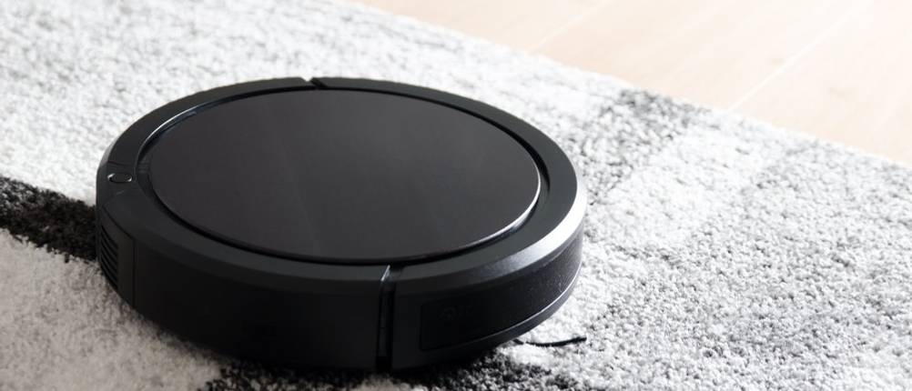 Getesteter Staubsauger-Roboter von iRobot saugt auf einem grau-schwarzen Teppich.
