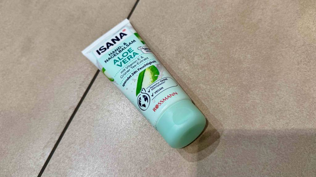 Blick auf den Deckel einer Tube getestete Aloe-Vera-Handcreme, die auf hellen Fliesen liegt.