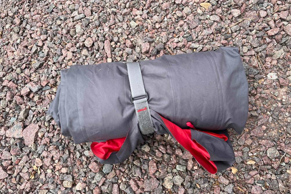 eine zusammengerollte grau-rote Isomatte auf einem Steinboden
