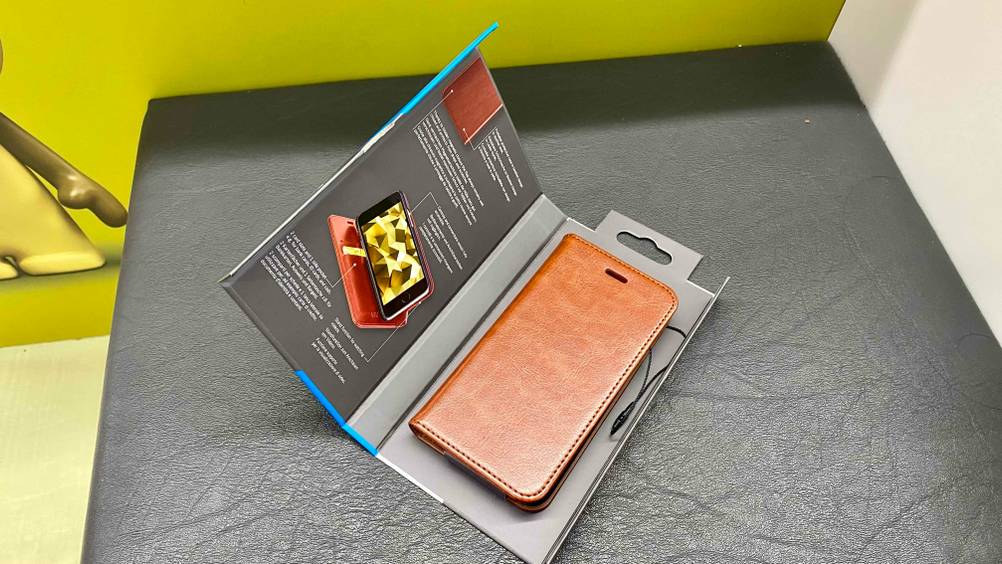 Im Test: Eine IPhone-SE-Hülle liegt in geöffneter Verpackung auf einer Lederfläche.