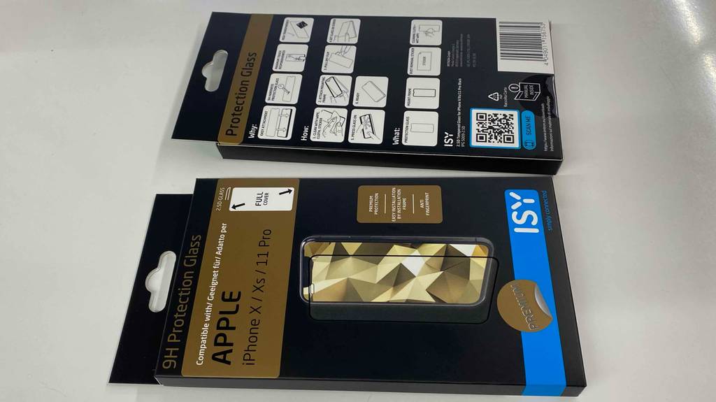 Zwei iPhone-X-Panzerfolien im Test: ihre Verpackungen liegen auf einem hellen Untergrund.