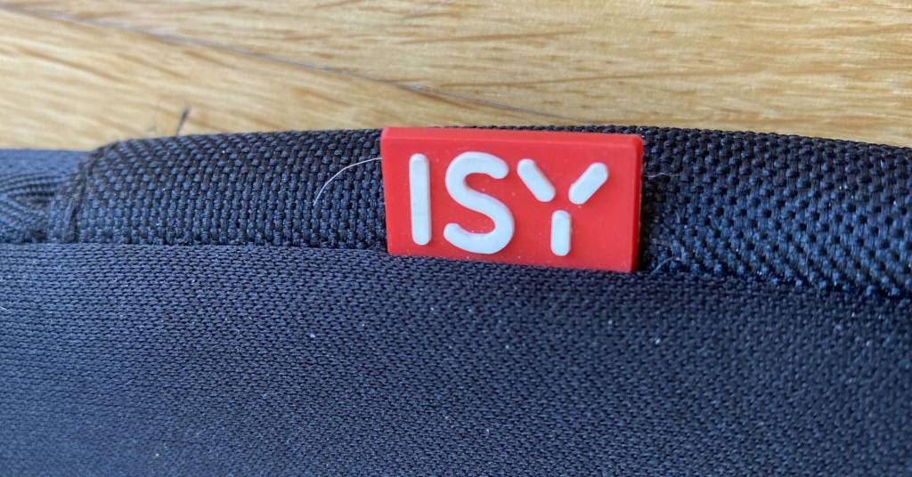 Laptop-Sleeve-Test: Detailansicht des Randes inklusive rotem Isy Markenzeichen eines blauen Gewebes auf Holzuntergrund.