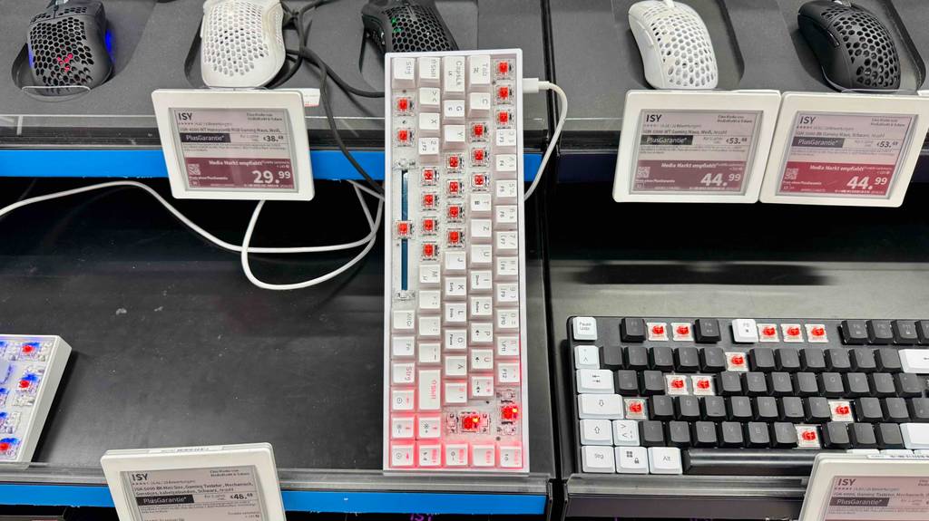 Eine getestete Mini-Gaming-Tastatur steht hochkant angelehnt an eine Regalfläche mit Mäusen.