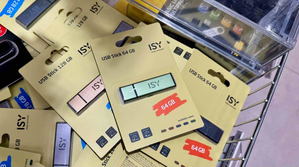 Mehrere getestete USB-Sticks mit 64 GB Speicher liegen in der gelben Verpackung eingeschweißt in einem Einkaufskorb.