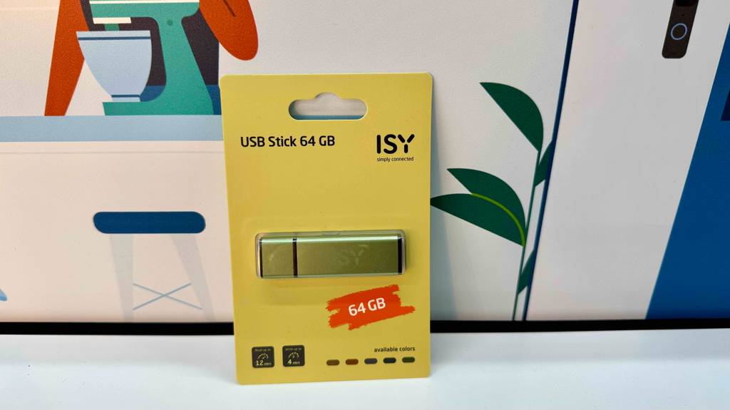 Die gelbe Verpackung eines USB-Sticks 64 GB im Test lehnt an einer Posterwand.