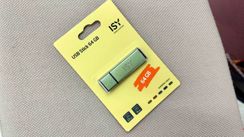 Ein USB-Stick 64 GB im Test liegt innerhalb seiner gelben Verpackung auf einem beigefarbenen Stoff.