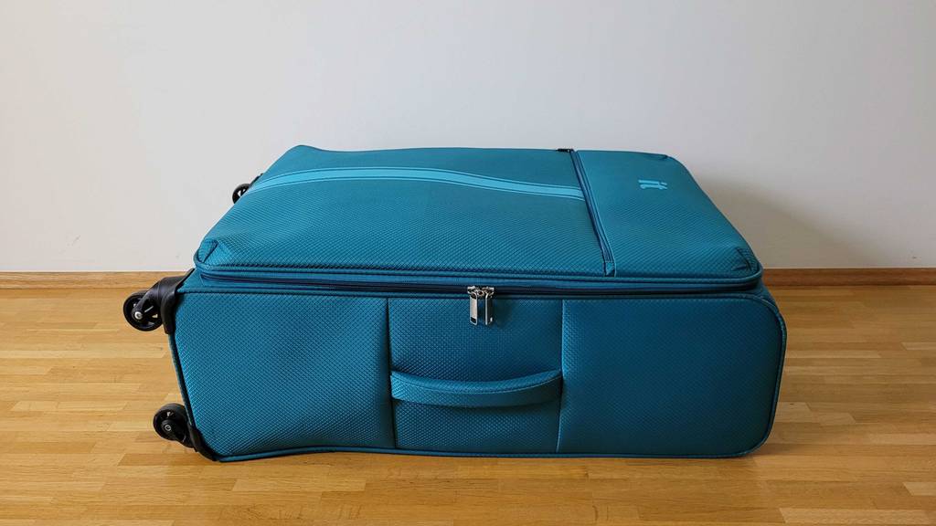 Im Test. Mittelgroßer blauer Koffer liegt in einem Zimmer.