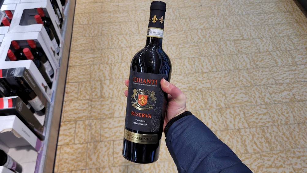 Eine Hand hält eine Flasche des italienischen Rotweins hoch.