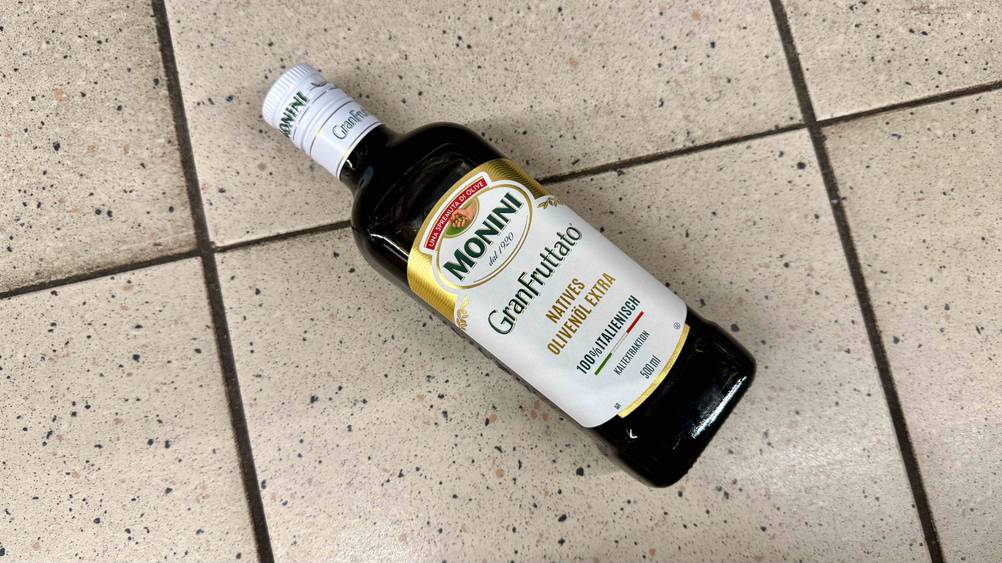 Auf einem Fließenboden liegt eine Flasche des getesteten italienischen Olivenöls.