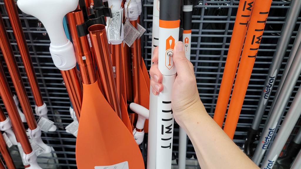 Eine Hand klickt zum Testen auf den Klickknopf eines Carbon Paddel SUP.