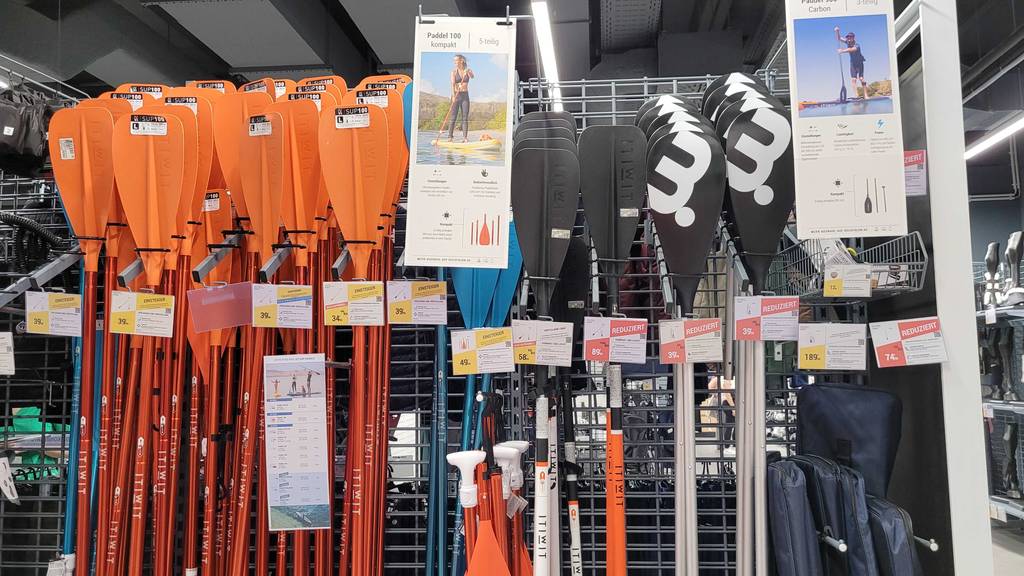 Carbon Paddel Sup im Test: Mehrere Paddel stehen aufgereiht in einem Gitterregal.