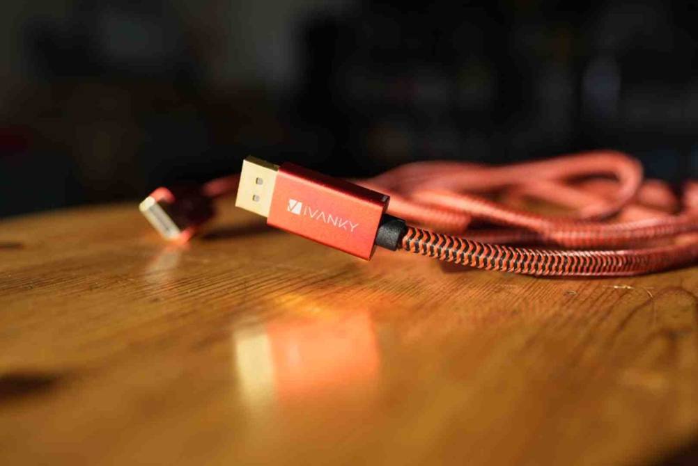 DisplayPort-Kabel im Test: Nahaufnahme des vergoldeten Steckers eines rosa IVANKY-Kabels, das auf einem Holztisch liegt.