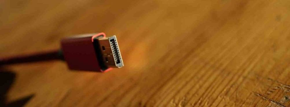 DisplayPort-Kabel-Test: Nahaufnahme des vergoldeten Steckers eines rosa Kabels vor einem Holzhintergrund.