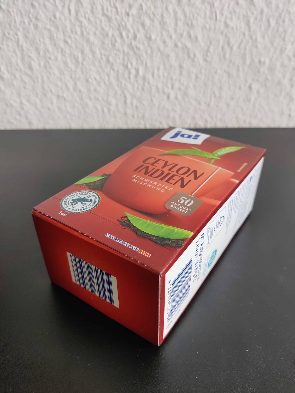 Nahaufnahme des Bodens einer Packung des getesteten Ceylon-Tees auf einer dunklen Fläche.