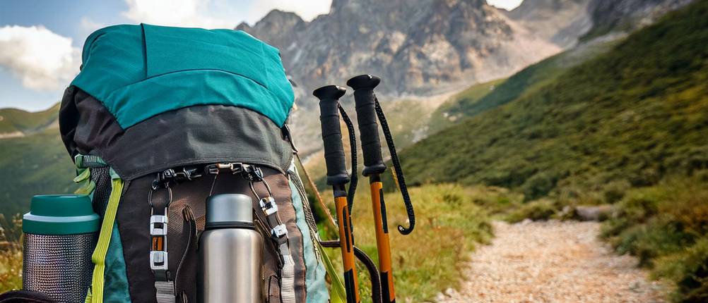 Jack-Wolfskin-Rucksack-Test: Rucksack samt Equipment auf einem Schotterweg vor einer Bergkulisse