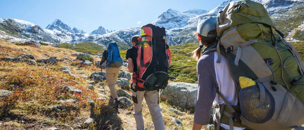 Jack-Wolfskin-Rucksack-Test: Gruppe, die durch eine Berglandschaft bei strahlendem Sonnenschein wandert