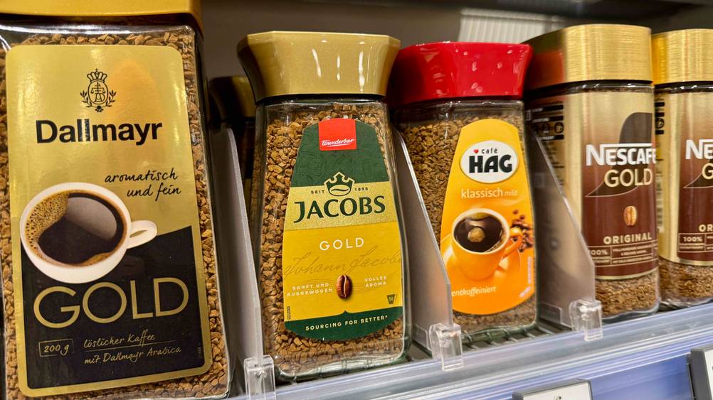 In einem Regal stehen mehrere Gläser des Jacobs-Kaffees im Test neben anderen Produkten.