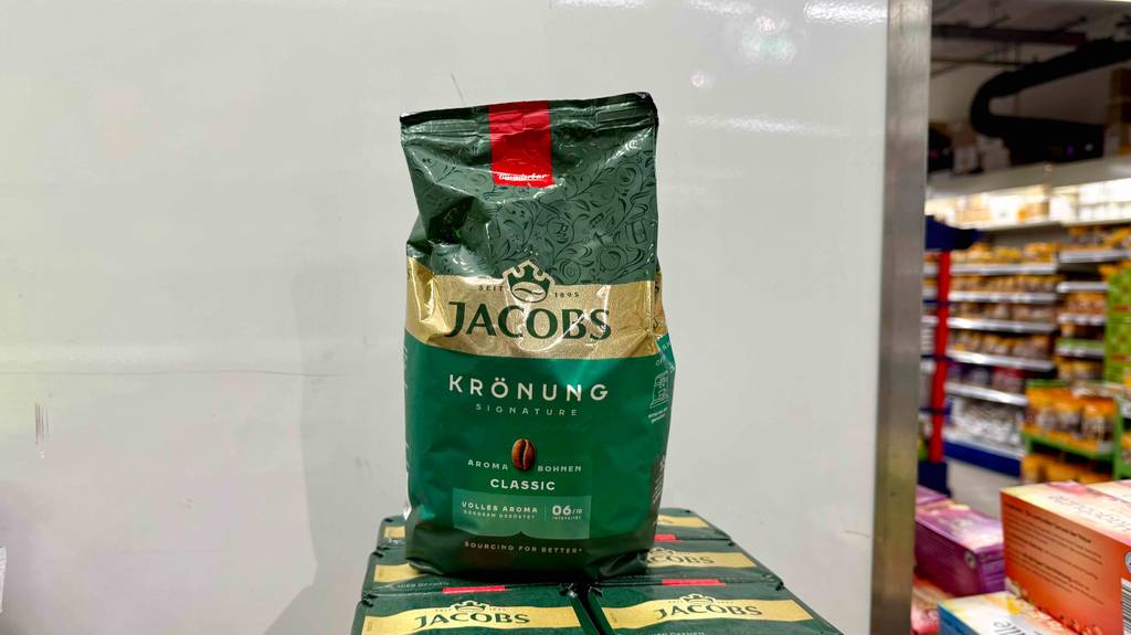 Frontansicht einer Packung getesteter Jacobs Kaffeebohnen, die auf einem Stapel Packungen steht.