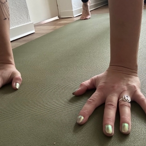 Reise-Yogamatte im Test: Hände auf grüner Yogamatte.